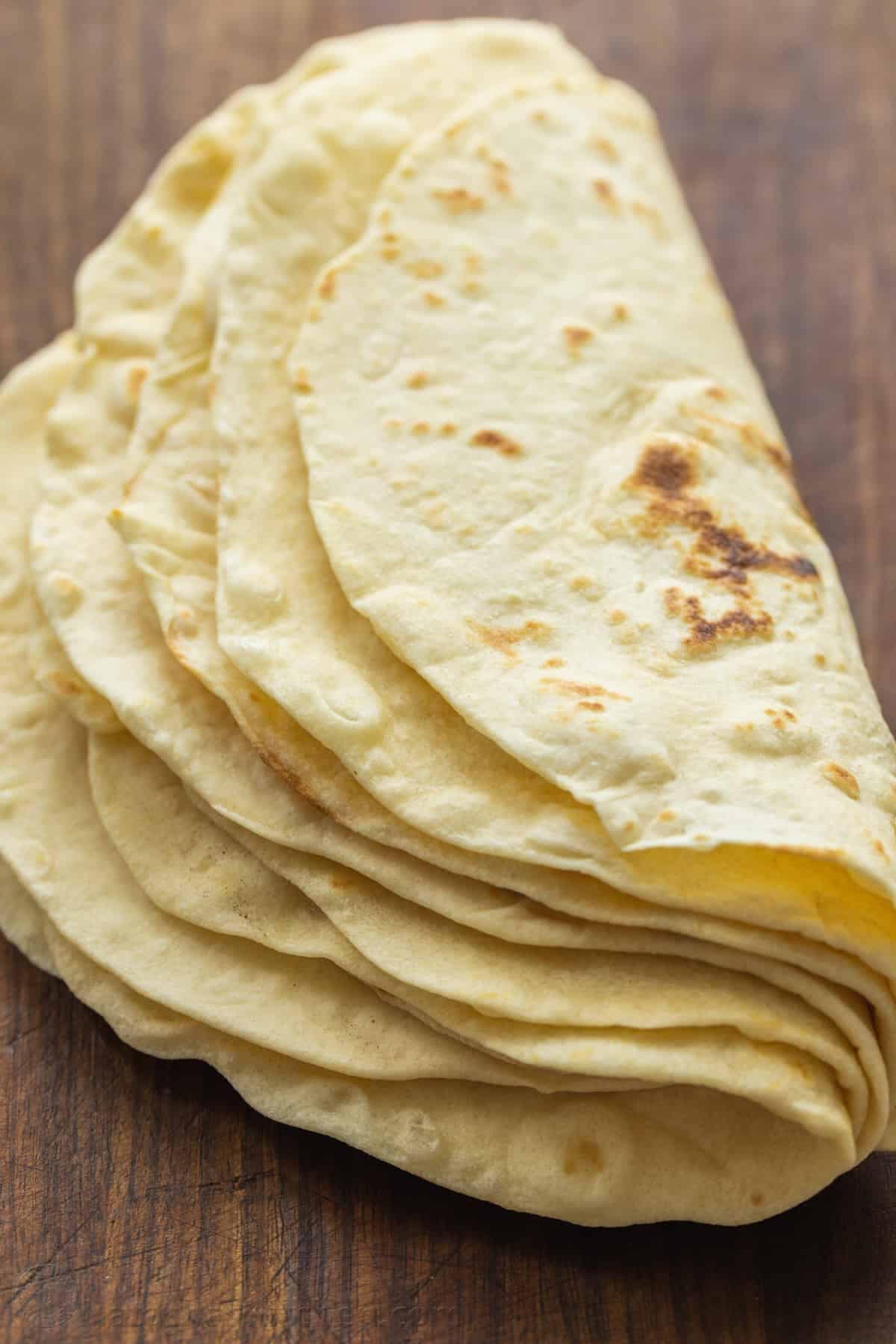 Make the best Flour Tortillas with just 5 ingredients! Use these soft homemade flour tortillas for tacos, quesadillas, burritos, and more. A stack of homemade flour tortillas folded in half.